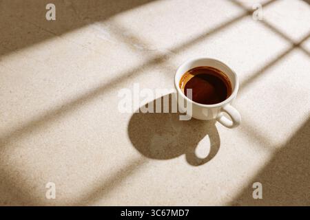 A cup of hot black coffee on a table in the sunlight Stock Photo
