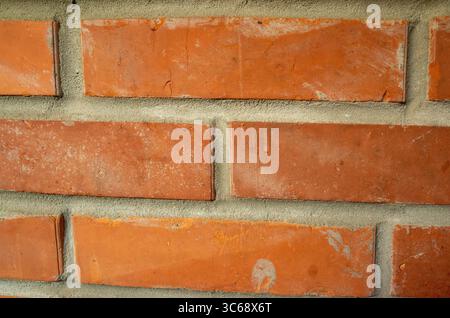 Brick wall with a few bricks missing. The wall is red and has a rough texture. The missing bricks give the wall a somewhat unfinished look Stock Photo