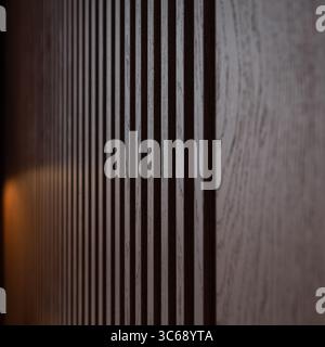Brown wooden louvers inside a dark room creating a striped background. Close-up view of wooden grain texture. Stock Photo