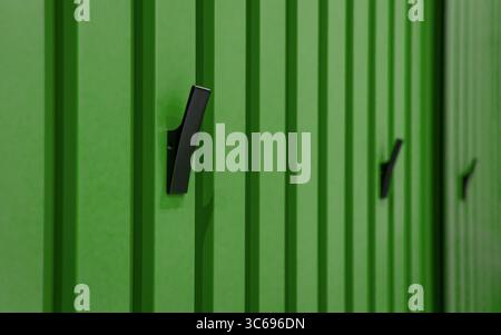 Green wall with black hanging hooks. Wall paneling with vertical planks and row of black metal hooks. Stock Photo