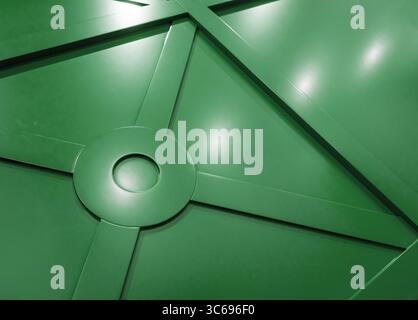 Green wall paneling with geometric pattern. Satin wall panel surface reflecting bright lights. Stock Photo