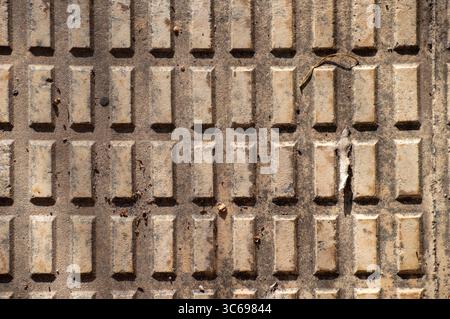 Full frame texture background of dirty concrete tactile paving tiles with rectangular raised pattern on a sidewalk. Stock Photo