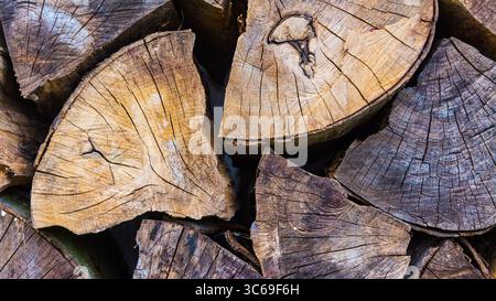 Closeup old cracked wooden logs chopped on part in artistic rustic woodpile background. Beautiful detail an abstract mosaic of stacked raw wood blocks. Stock Photo