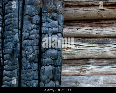 Close-up texture showing contrasting weathered wood surfaces - charred black timber alongside natural aged wooden planks creating a rustic pattern. Stock Photo