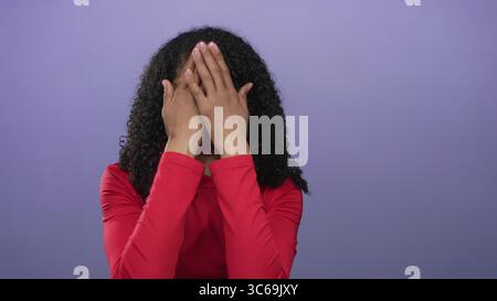 African american woman with extended hand makes a stop gesture in studio against purple background; rejection. Stock Photo