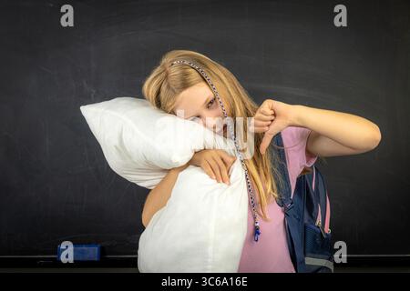 Tired elementary school student hugging pillow Stock Photo