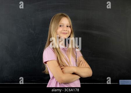 Confident schoolgirl smiling with folded arms Stock Photo