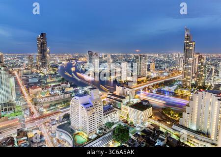Bangkok skyline taken at sunset featuring The Chao Phraya River and towering skyscrapers bathed in the warm golden light Stock Photo