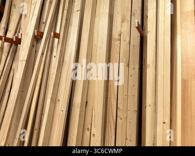 Shelves filled with neatly arranged wooden planks in a workshop radiate a warm, natural vibe. The light reflects off the wood, showcasing its textures Stock Photo