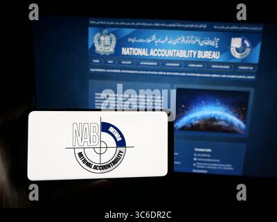 Stuttgart, Germany - 06-20-2025: Person holding smartphone with logo of Pakistan National Accountability Bureau (NAB) on screen in front of website. Stock Photo