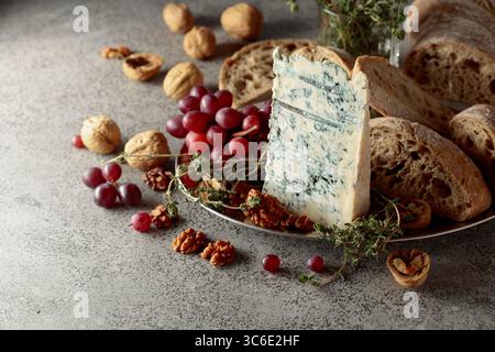 Gorgonzola with ciabatta, walnuts, grapes, and thyme on a gray stone background. Stock Photo