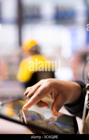 Smart factory engineer developing robotic machinery with CAD software on tablet. Closeup of technician using digital interface to streamline industrial automation processes in manufacturing plant. Stock Photo