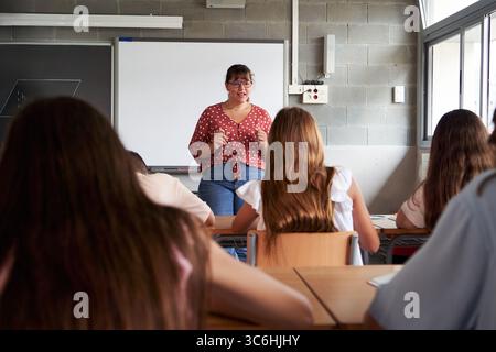 High school teacher explaining lesson to students in classroom. Stock Photo