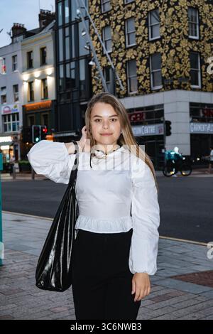 A selfassured young woman confidently poses in a stylish outfit at an exciting and vibrant urban location Stock Photo