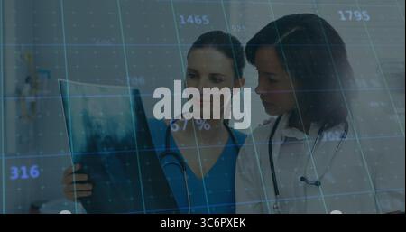 Two doctors in scrubs and lab coat studying X-ray film in clinic, with digital data overlay Stock Photo