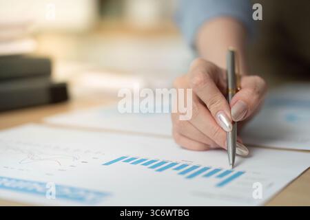 Data Analysis. Woman reviewing financial graphs and charts with a pen. Stock Photo