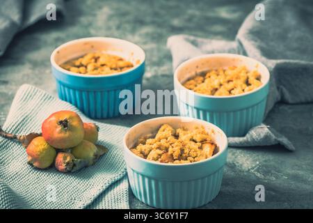 Apple crumble in small blue molds on a rustic gray table Stock Photo