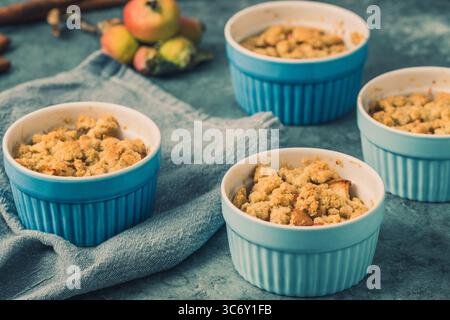 Apple crumble in small blue molds on a rustic gray table Stock Photo