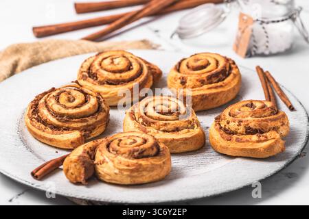 Homemade cinnamon rolls on white plate on white marble background Stock Photo