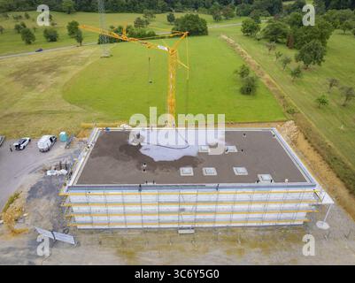 Drone shot of a construction site with crane and partially constructed building on a large green area, green roof, house construction, climate neutral Stock Photo