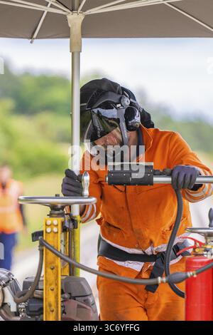 A worker in an orange suit and helmet works under an umbrella on a railway line, grinding work on the Hermann Hesse railway, Ostelsheim, district of C Stock Photo