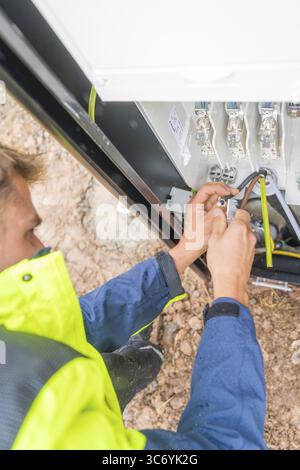 Worker fixing cables with tools in an electrical installation, assembly of a charging station for electric cars, Calw, Germany Stock Photo