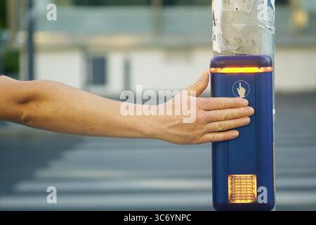 Hand pushing crosswalk signal button. Urban safety measure enabling pedestrians to request a safe traffic stop. Technology supporting accessibility Stock Photo