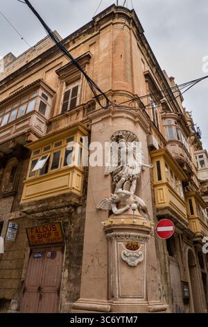 St Michael the Archangel vanquishing the devil statue on building corner in city of Valletta in Malta. Stock Photo