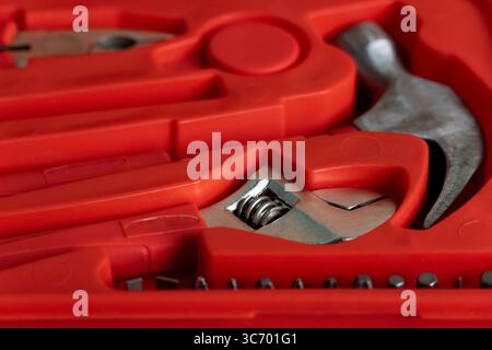 Detailed close-up image of various hand tools neatly arranged in a bright red plastic case, highlighting metallic textures and organized compartments Stock Photo