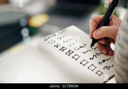 Checklist notebook task progress accuracy. Close-up hand holding pen while marking completed tasks grid notebook. Symbol of productivity, precision, q Stock Photo