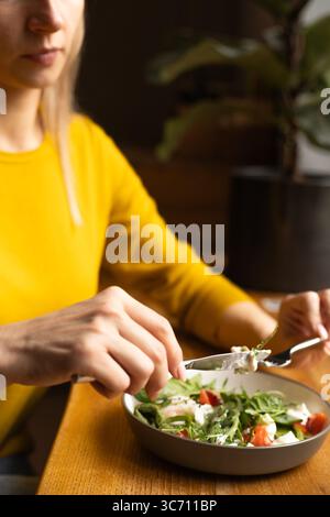 Close-up of female hands holding fork and knife, fresh salad with eggs Stock Photo