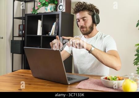 Focused young man with hearing impairment using sign language gestures for a professional video conference on his computer from his home office. Stock Photo