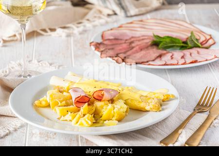 Plate with asparagus, potatoes, ham and hollandaise sauce on white wooden background Stock Photo