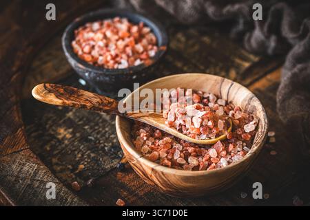 Himalayan salt in a wooden bowl on dark wooden background Stock Photo