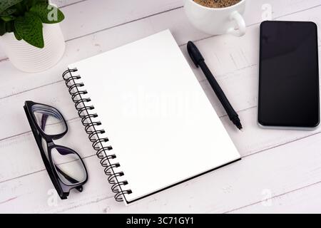 Blank notepad, smartphone, eyeglasses on a desk flat lay Stock Photo