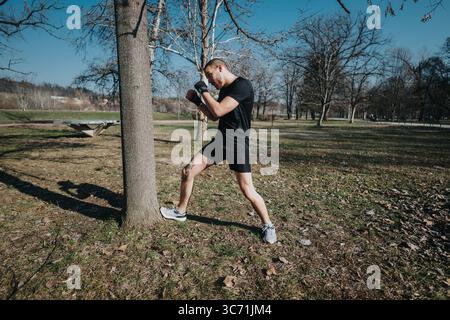 Man Practicing Boxing Stance Outdoors in a Park During a Bright Sunny Day Stock Photo