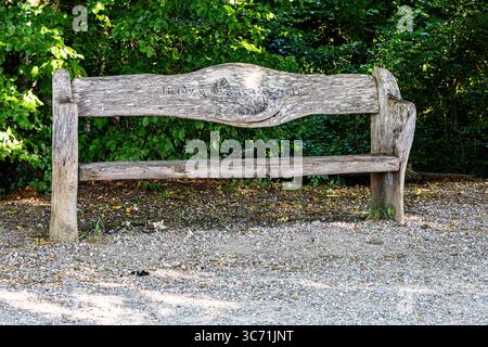 Rustic wooden bench made from natural logs with the names Heidy Werner Zerkle engraved into the backrest, placed in a peaceful forest area near Kreuzl Stock Photo