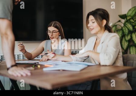 Two women sitting at a table collaborating on business documents Stock Photo