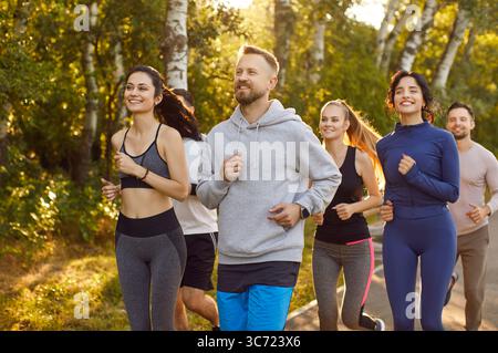 Group of young, active people enjoying outdoor jogging in summer park Stock Photo