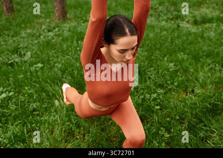 A young beautiful woman demonstrates impressive yoga flexibility in a vibrant green park. Stock Photo