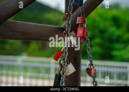 View of many colorful heart-shaped padlocks hanging on a chain. Symbol of eternal love. Stock Photo