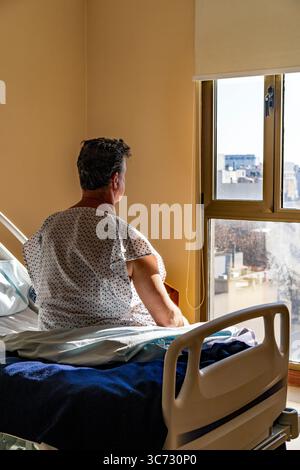 Back view of patient observing the outside world through a window. Stock Photo