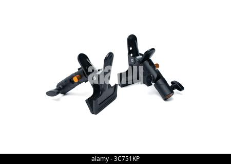 Two durable black clamps with orange handles lying side by side, isolated on a white background. Used to hold objects in place during photography or s Stock Photo