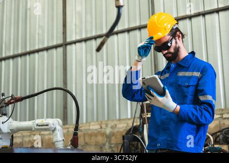 robotics engineer checking a robot arm in an industrial factory Stock Photo