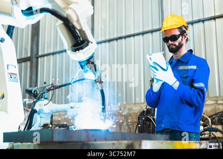 robotics engineer checking a robot arm in an industrial factory Stock Photo