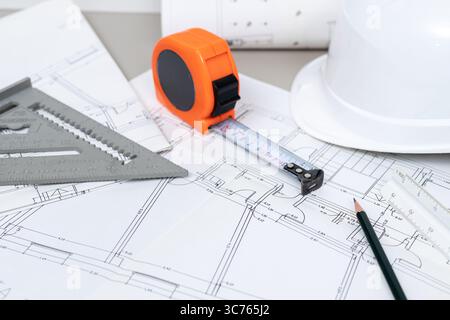 Close up of a builder workbench with blueprints, tape measure, and other construction tools Stock Photo