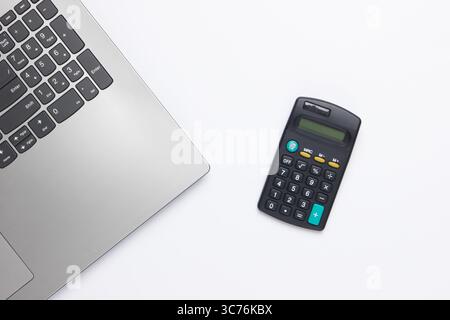 Economic calculation, profit analysis. Calculator and laptop on a white background. Top view Stock Photo