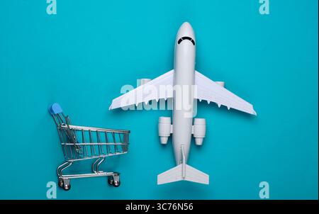 Flat lay composition. Air delivery, shopping, logistics. Figurine of shopping trolley, airplane on blue background. Top view Stock Photo