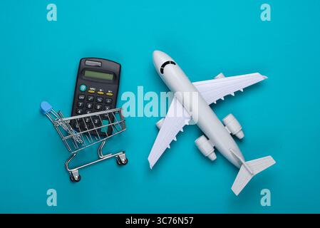 Flat lay composition. Cost calculation of Air delivery, shopping, logistics. Figurine of shopping trolley, airplane, calculator on blue background. To Stock Photo