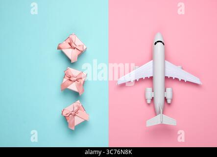 Air delivery. Plane figurine and gift boxes on pink blue pastel background. Flat lay. Top view Stock Photo